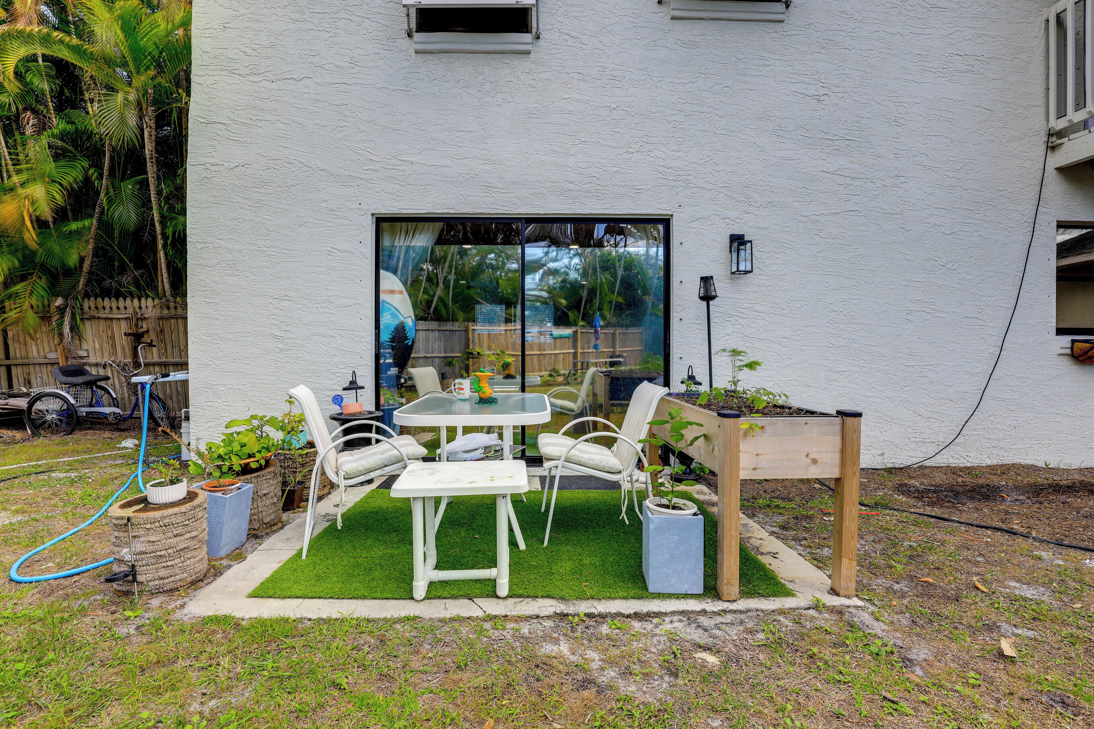 A patio with a table and chairs, surrounded by potted plants and a small garden.