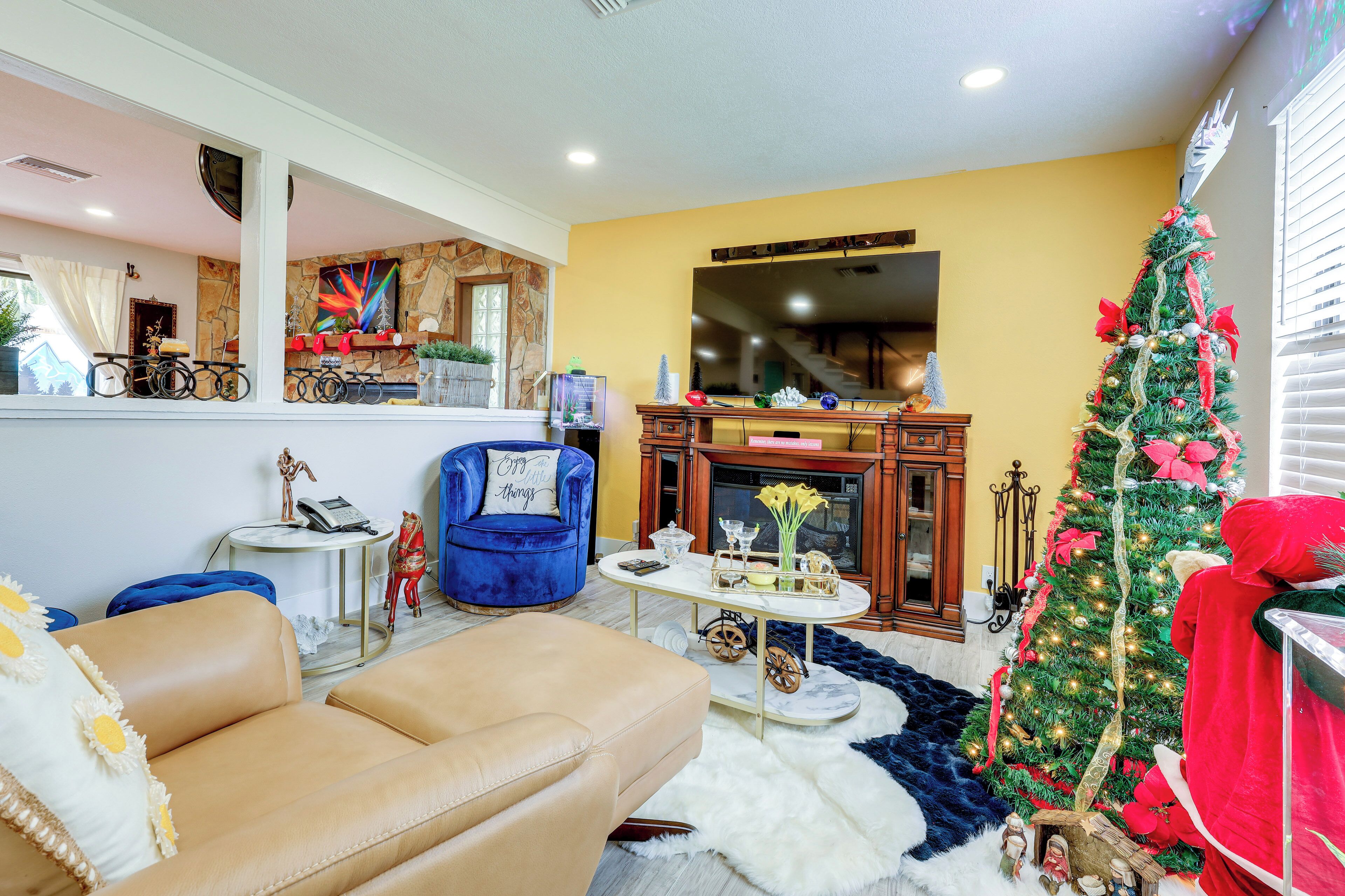Een woonkamer met een open haard, een kerstboom en een bank.