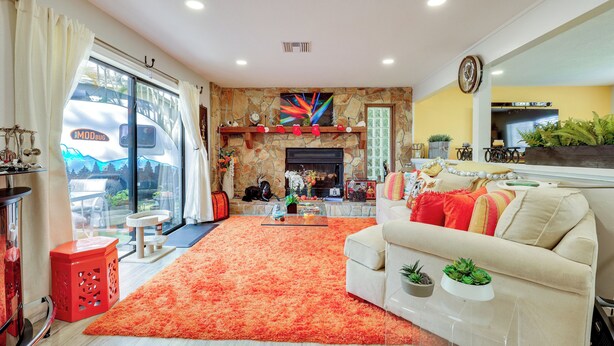 A living room with a fireplace, a sofa, a coffee table, and a large window with curtains. - 10 Mi to Public Beaches: Port St Lucie Getaway (Port Saint Lucie)