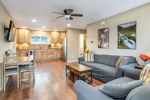 A modern kitchen with wooden cabinets, a dining area with a table and chairs, a gray sofa, and a ceiling fan. - Denver Home w/ Patio Near City Park & Cherry Creek (Denver)
