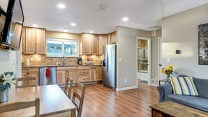 A modern kitchen with wooden cabinets, a stainless steel refrigerator, and a dining area with a wooden table and chairs. - Denver Home w/ Patio Near City Park & Cherry Creek (Denver)