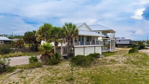 A coastal house with a balcony, surrounded by palm trees and a sandy landscape. - ENJOY THE WONDERFUL natural daylight in this comfortable home (St. George Island)