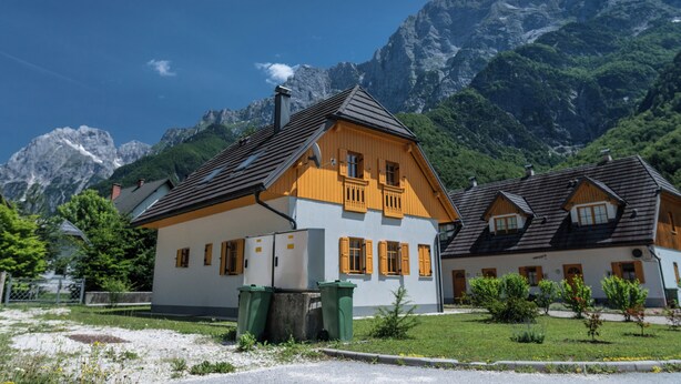 A traditional chalet with a sloped roof, wooden shutters, and a chimney. It is surrounded by a well-maintained lawn and a mountain backdrop. - House Parabola – 4-Bedroom Mountain Retreat with Breathtaking Views, Sleeps 10 (Log pod Mangartom)