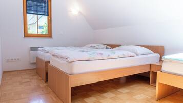 A bedroom with a wooden bed, a window with blinds, and a wall-mounted light fixture.