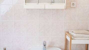 A bathroom with a white sink, a mirror above it, and a towel rack to the left.