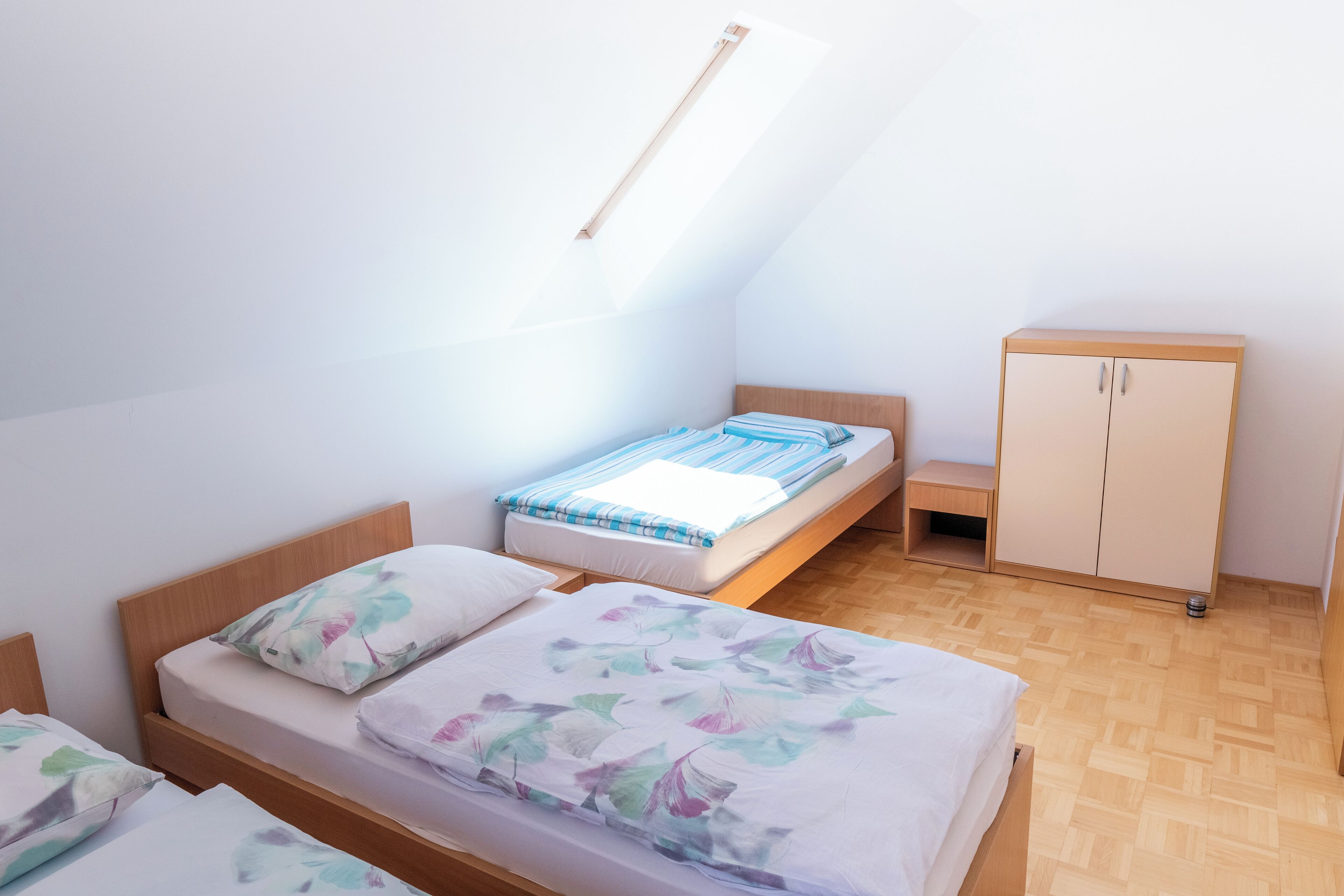 Une chambre de type dortoir, avec deux lits, une armoire et un puits de lumière.
