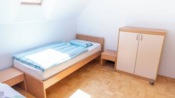 A small, single-bed room with a wooden headboard and a wooden wardrobe.