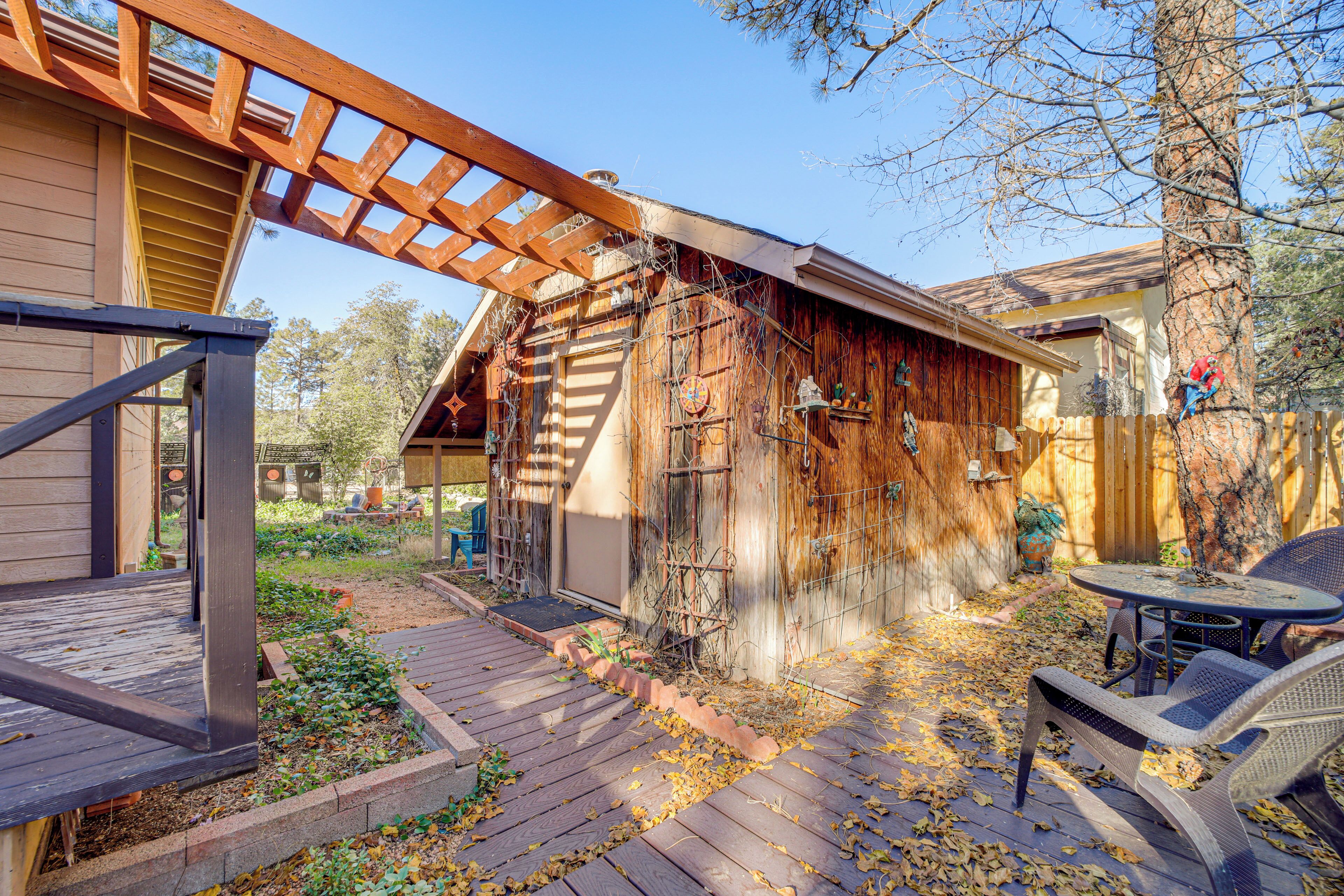 A wooden deck with a pergola, a covered patio area, and a fenced backyard with a wooden fence and a tree.