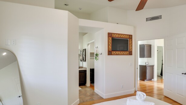 Un dormitorio con una cama grande, un espejo y vistas al baño y la cocina.
