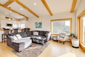A spacious living room with a gray sectional sofa, a coffee table, and a large window providing natural light. - Stroll to Shore: Retreat w/ Balcony in Gold Beach (Gold Beach)