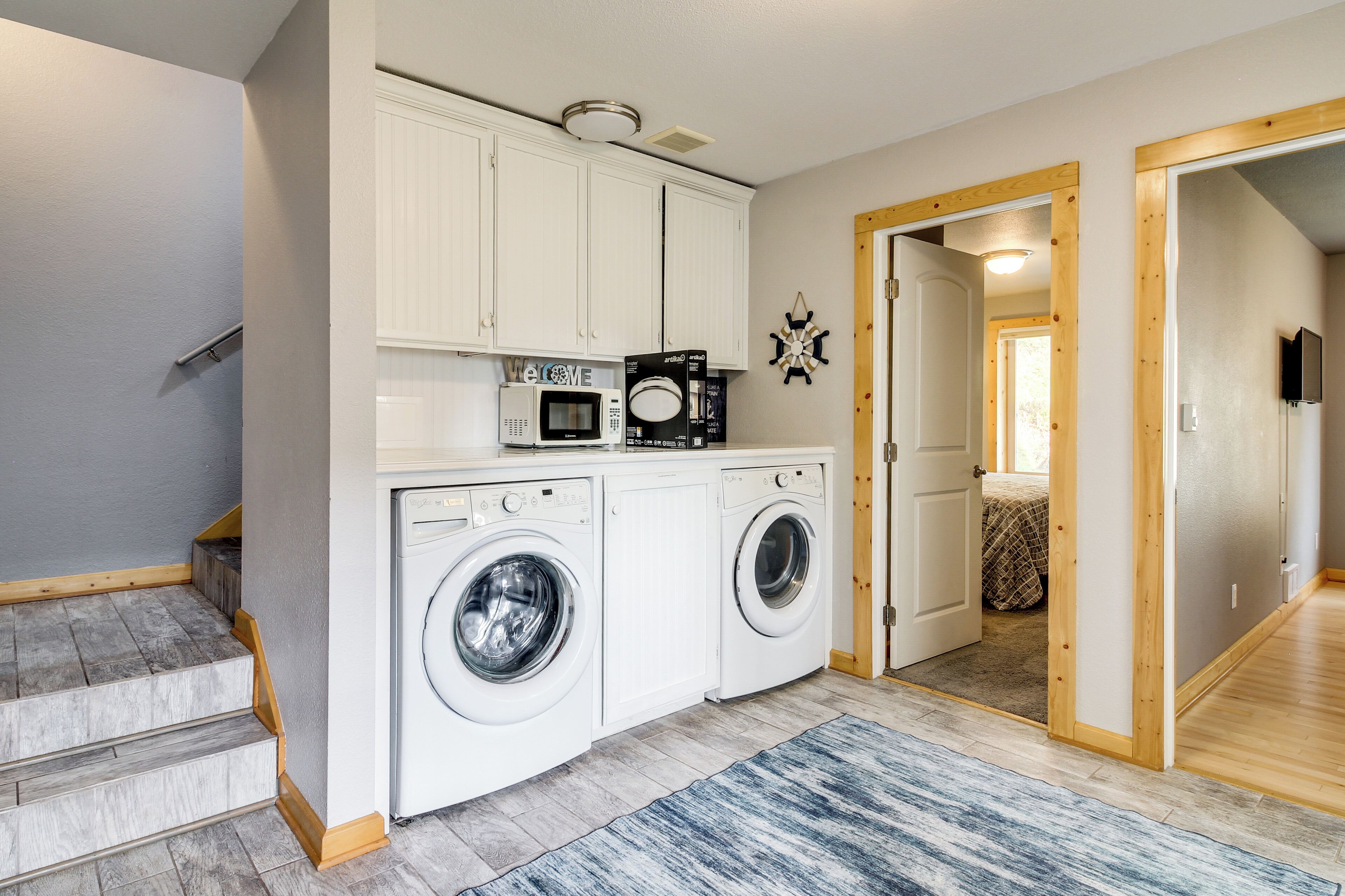 A laundry room with a washing machine and dryer, a microwave, and a ceiling fan.