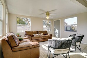 A spacious living room with a brown leather sofa, a black woven chair, and a ceiling fan. - Updated El Paso Home: Less Than 5 Mi to Ft Bliss! (El Paso)