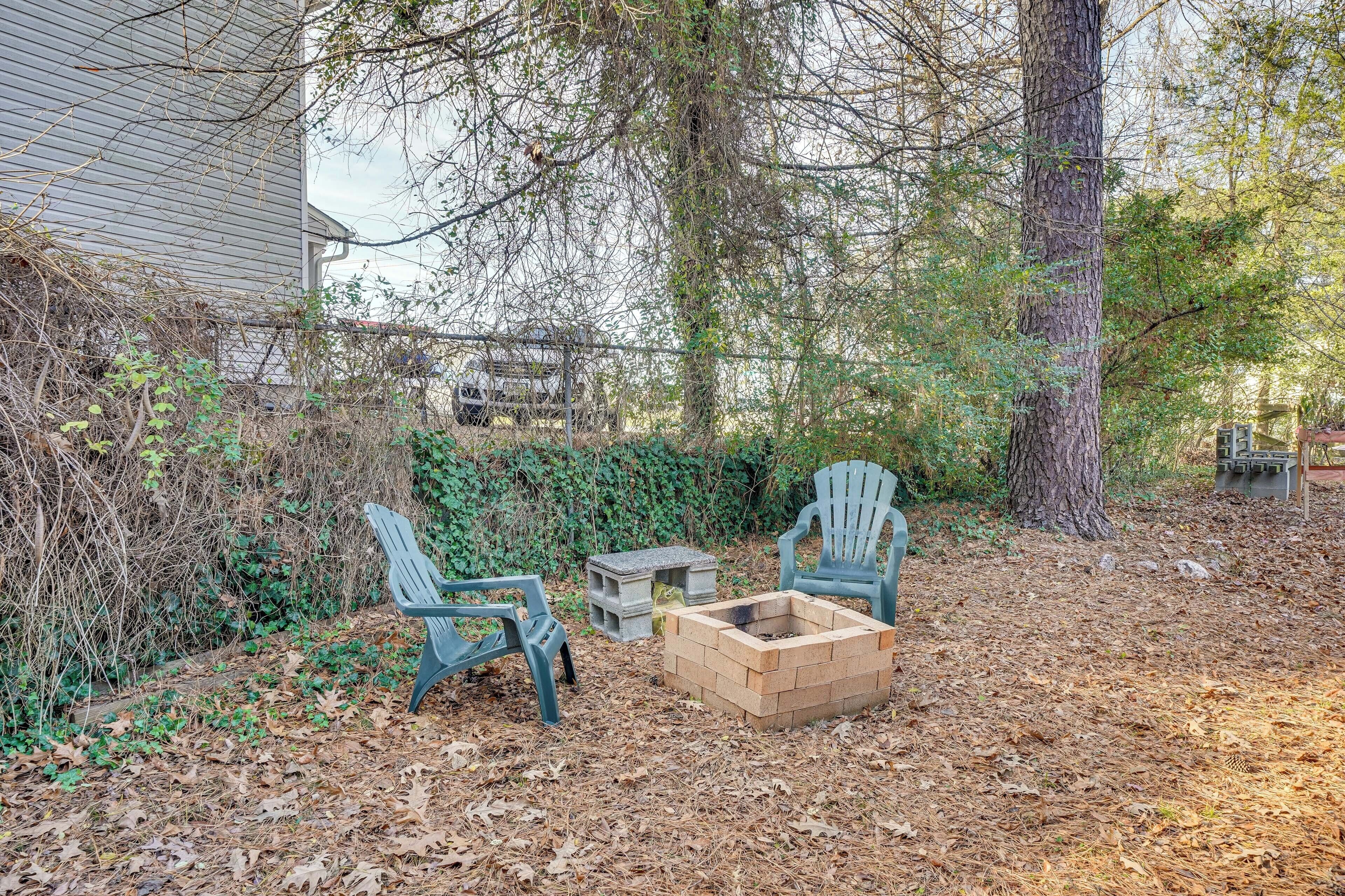 A backyard with two Adirondack chairs, a fire pit, and a wooden bench.