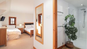 A bedroom with a bed, bedside tables, a mirror, a window, and a shower area. - Northbanks House (Thurso)