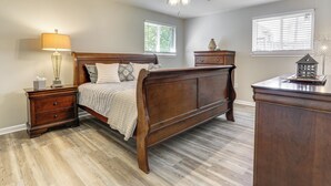 Ein Schlafzimmer mit einem hölzernen Bett, einem Nachttisch, einer Kommode und einem Deckenventilator.