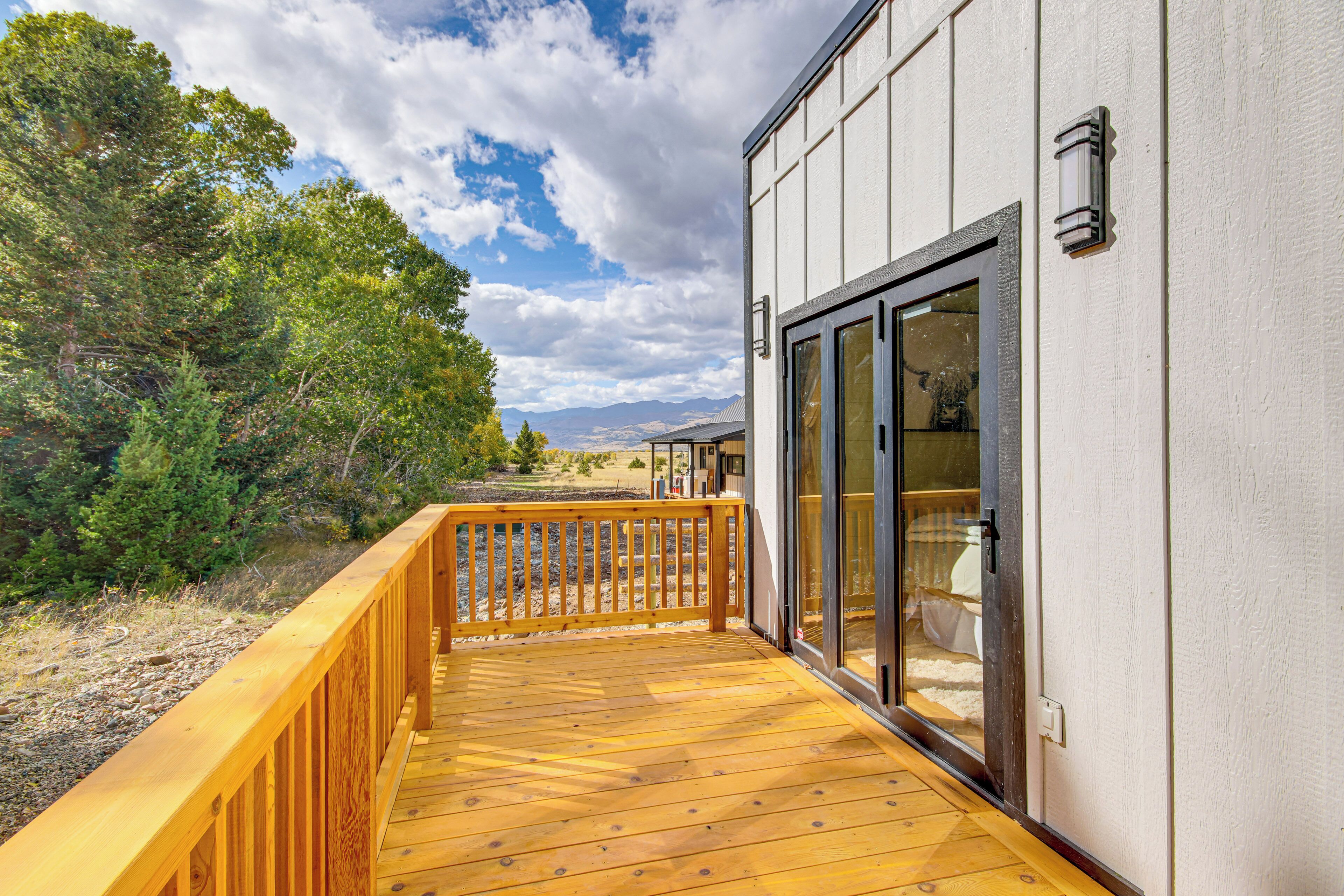 A wooden deck with a glass door leading to a room.