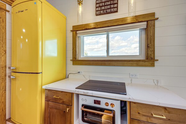 A kitchen with a yellow refrigerator, a built-in oven, and a window above the countertop.