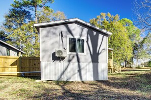 Une petite cabane à un seul étage, dotée d’une fenêtre et d’un climatiseur fixé sur le mur extérieur.