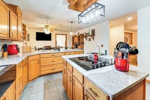 A modern kitchen with wooden cabinets, granite countertops, a built-in stove, and a ceiling fan. - Private 42-acre Sonora Estate Near National Parks (Sonora)