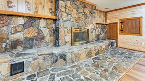 Una chimenea de piedra con puerta de cristal, vigas de madera y pared de piedra.