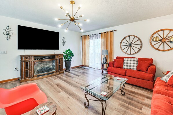 A living room with a flat-screen TV, a fireplace, a red sofa, a glass coffee table, and decorative wheels on the wall. - Private 42-acre Sonora Estate Near National Parks (Sonora)