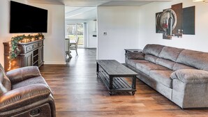 Een moderne woonkamer met een leren bank, een houten salontafel en een flatscreen televisie aan de muur.