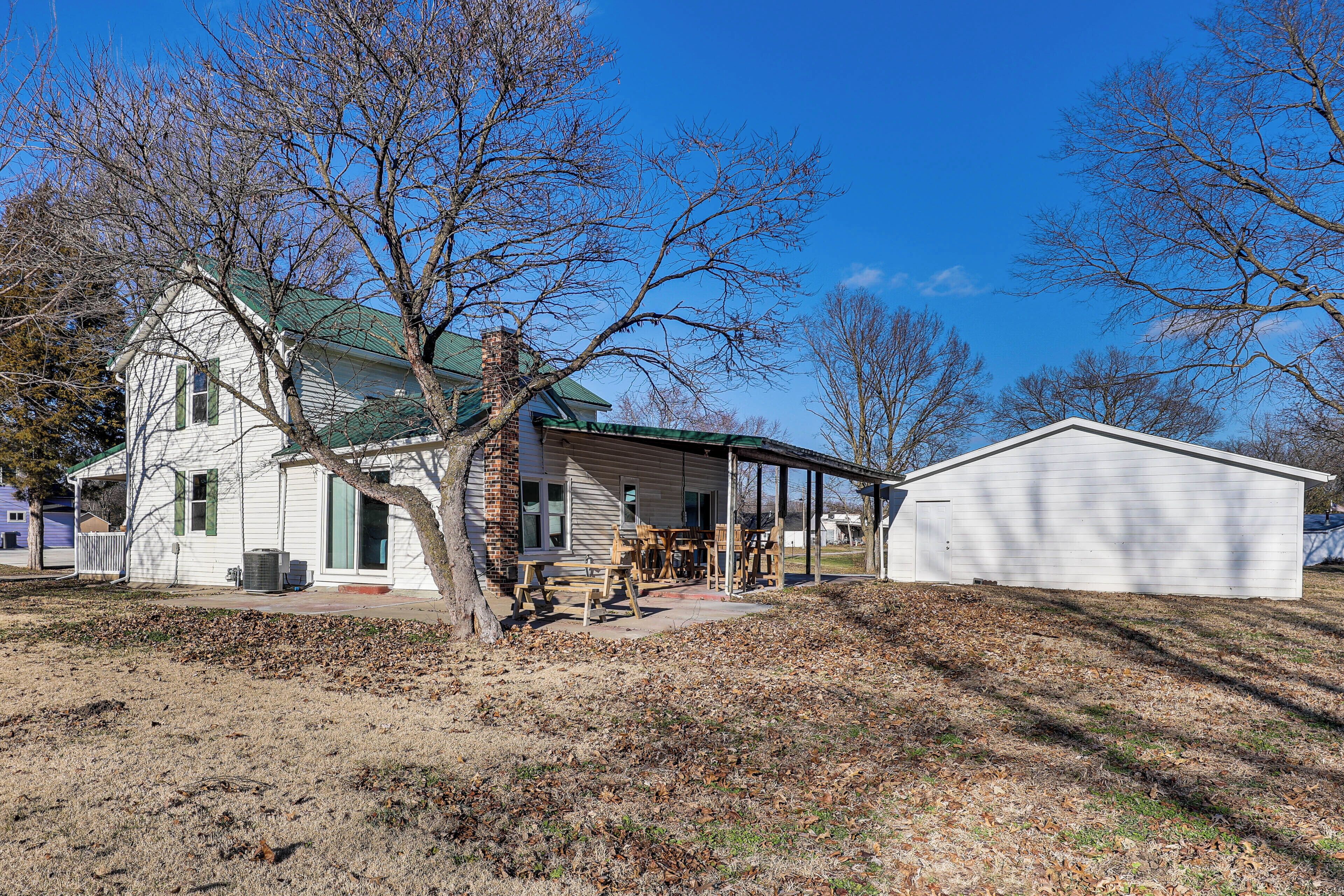 A two-story house with a green roof, a covered porch, and a detached garage.