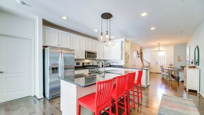 A modern kitchen with white cabinets, stainless steel appliances, and a central island with red bar stools. - Shuttle to Beach, Relax on Patio! Millville Escape (Millville)
