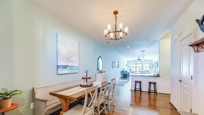 A dining area with a wooden table and chairs, a chandelier, and a view into the kitchen. - Shuttle to Beach, Relax on Patio! Millville Escape (Millville)