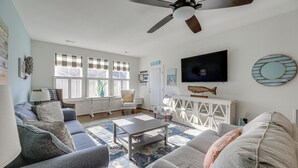 A living room with a ceiling fan, a television, and a large window with blinds. - Shuttle to Beach, Relax on Patio! Millville Escape (Millville)