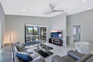 A modern living room with a sofa, coffee table, and TV. - Naples Park - Near Vanderbilt Beach! (Naples)