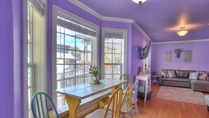 A room with a dining table, chairs, a sofa, and a window with blinds.