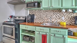 A kitchen with a microwave, stove, and various utensils.