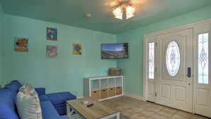 A living room with a blue sofa, a wooden coffee table, a white cabinet, and a door with a stained glass window. - New Listing! Rosewood Studio at Dusty Rose Inn | Main Street Creede (Creede)