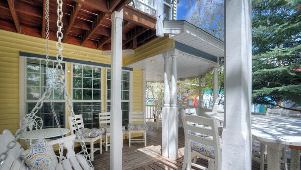 A covered outdoor seating area with white furniture and a wooden deck. - New Listing! Rosewood Studio at Dusty Rose Inn | Main Street Creede (Creede)