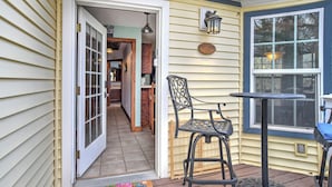 A covered porch with a door leading to a kitchen, a table with chairs, and a decorative rug. - New Listing! Roseview Loft at Dusty Rose Inn | Main Street Creede | (Creede)