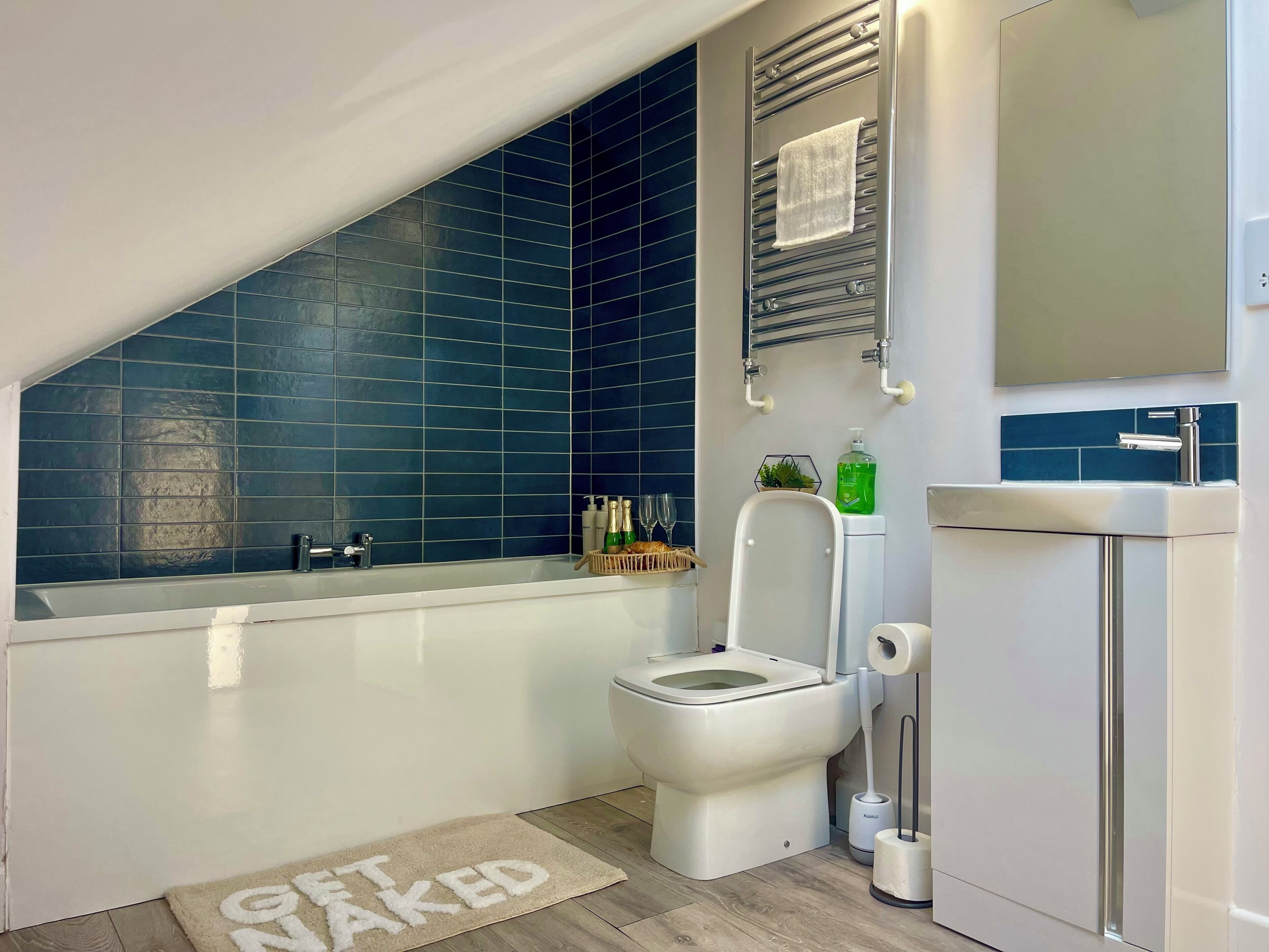 A modern bathroom with a bathtub, toilet, and a towel rack.