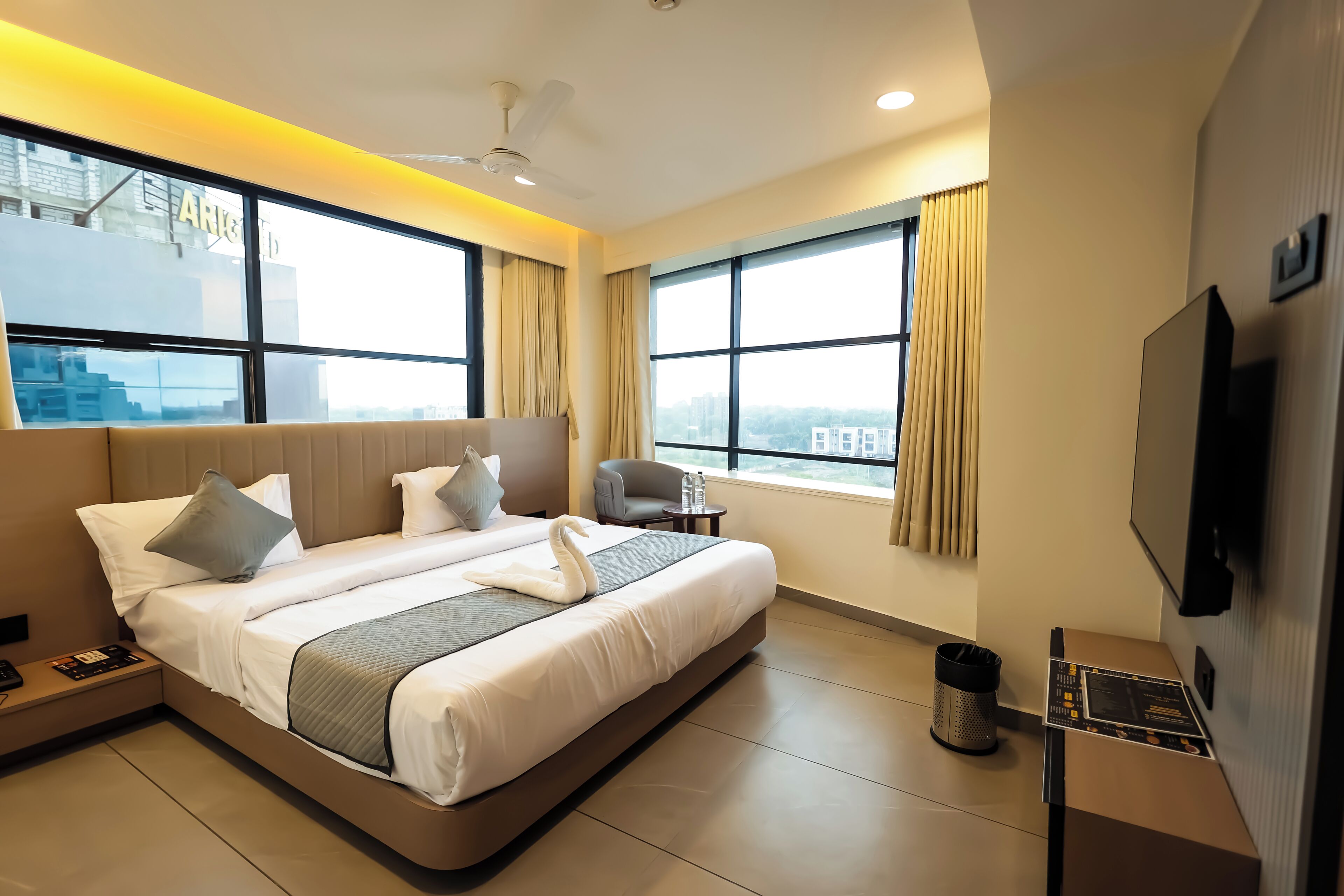 Een moderne hotelkamer met een groot bed, een televisie en uitzicht op de stad.