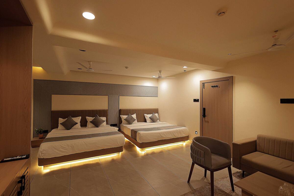 Una habitación de hotel moderna con dos camas, un sofá, una silla y un ventilador de techo.