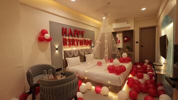 A bedroom with a bed, a bedside table, a chair, and a large number of balloons.