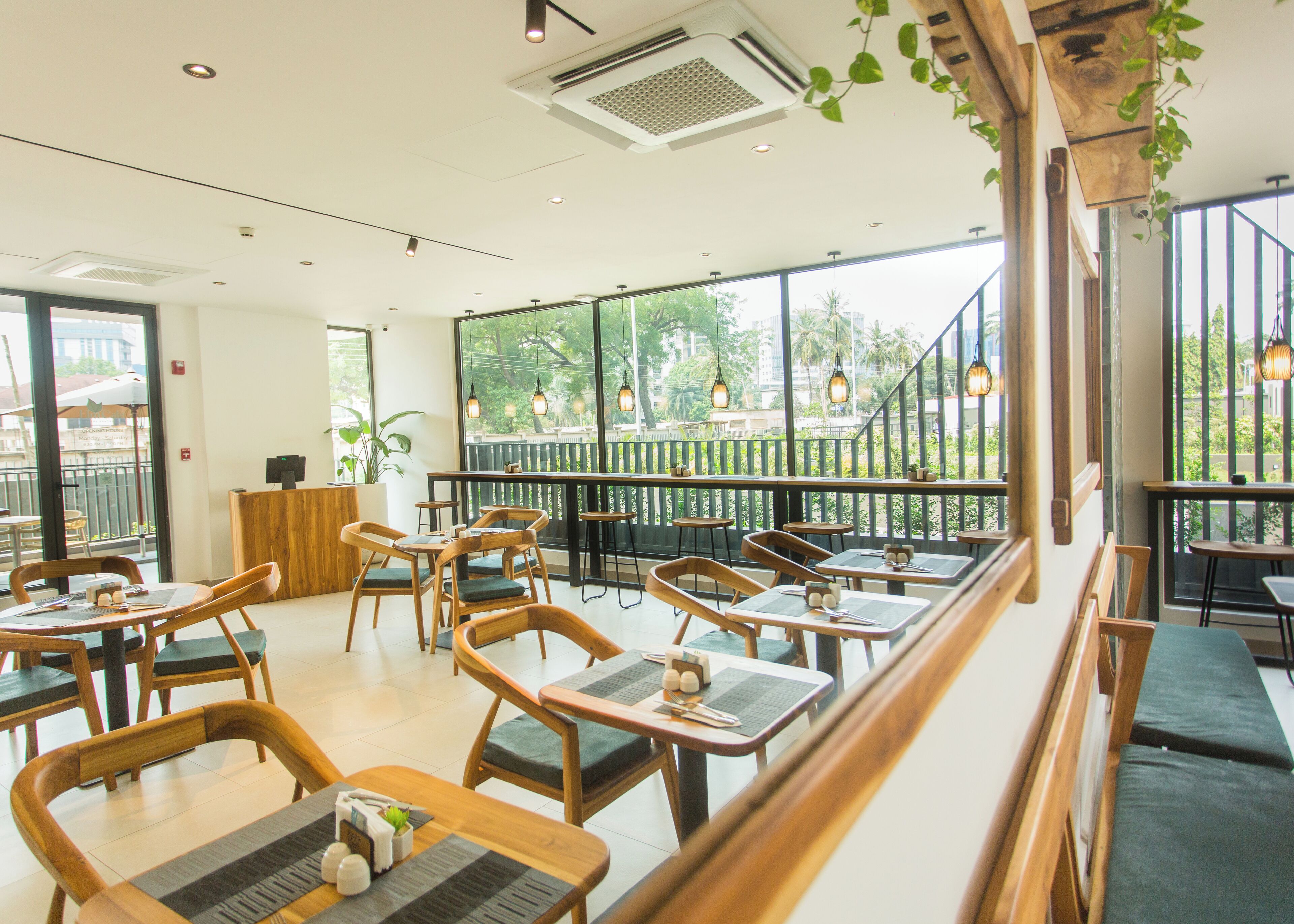 Un restaurant avec des meubles en bois, de grandes fenêtres et des luminaires suspendus.