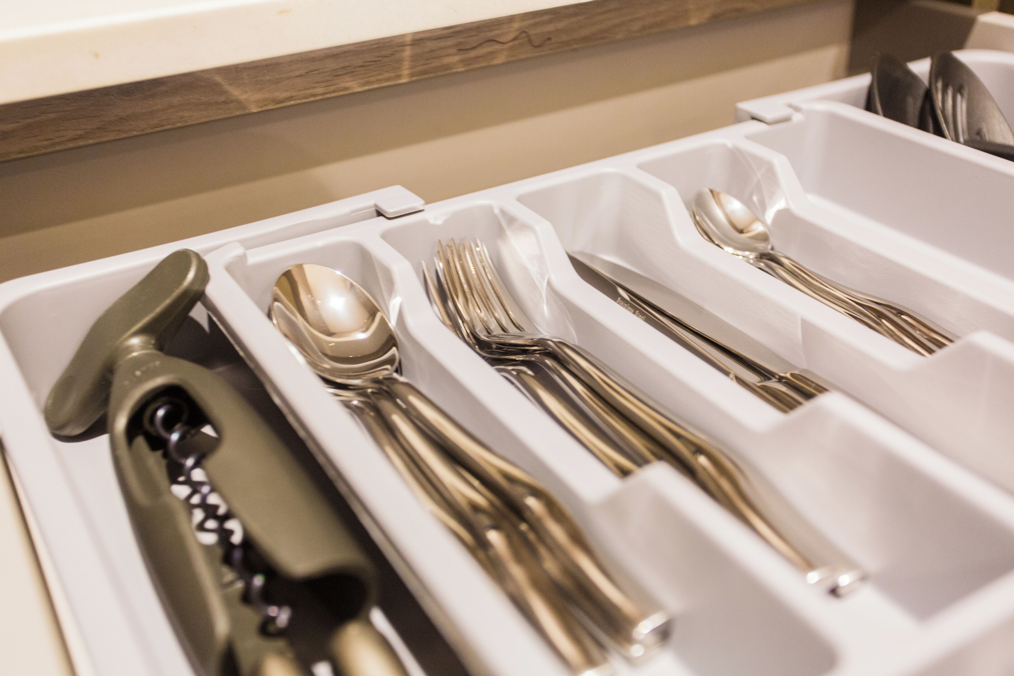 A drawer containing neatly organized cutlery including spoons, forks, and knives.