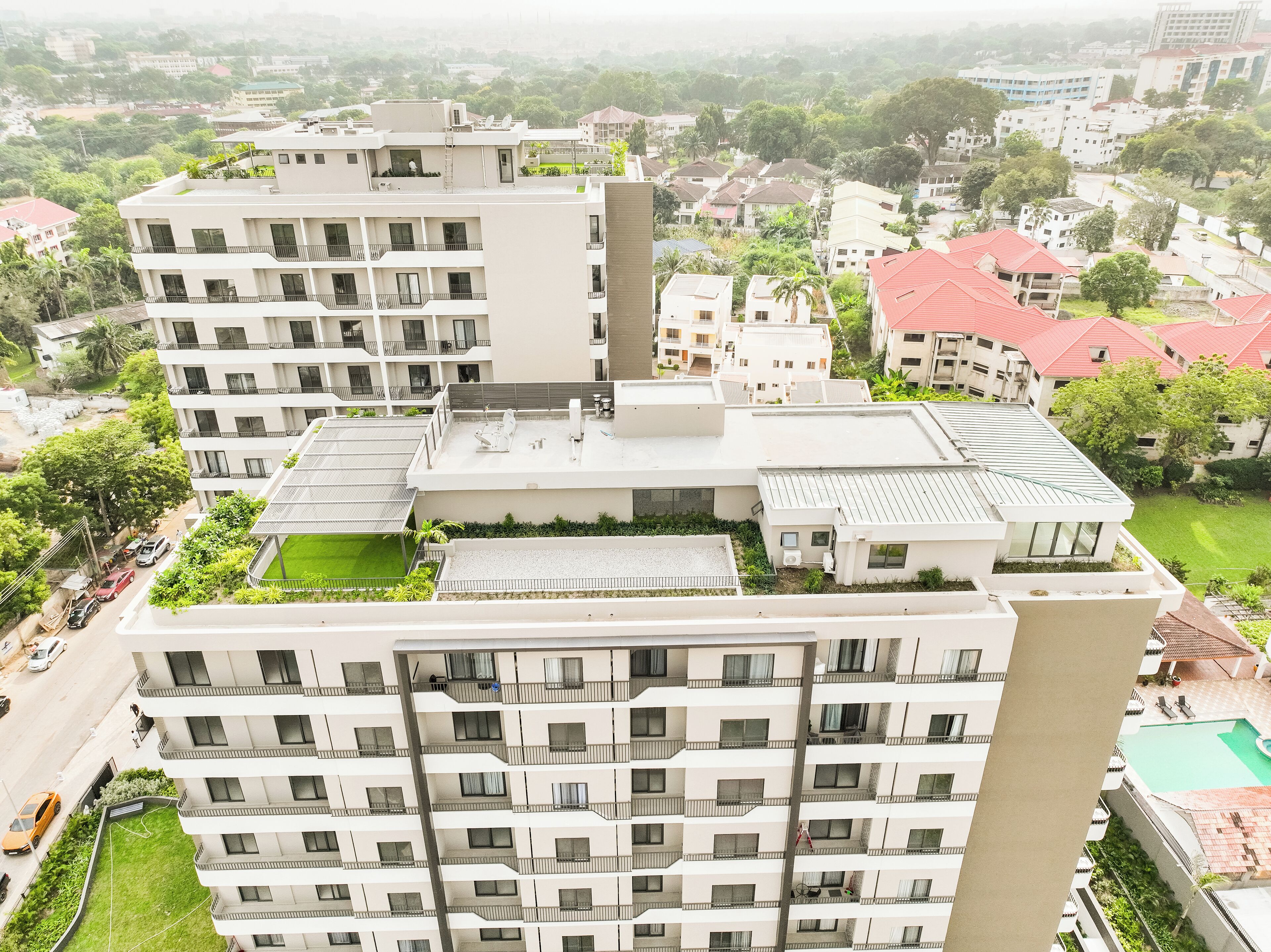 A high-rise residential building with multiple balconies, a rooftop garden, and a swimming pool.