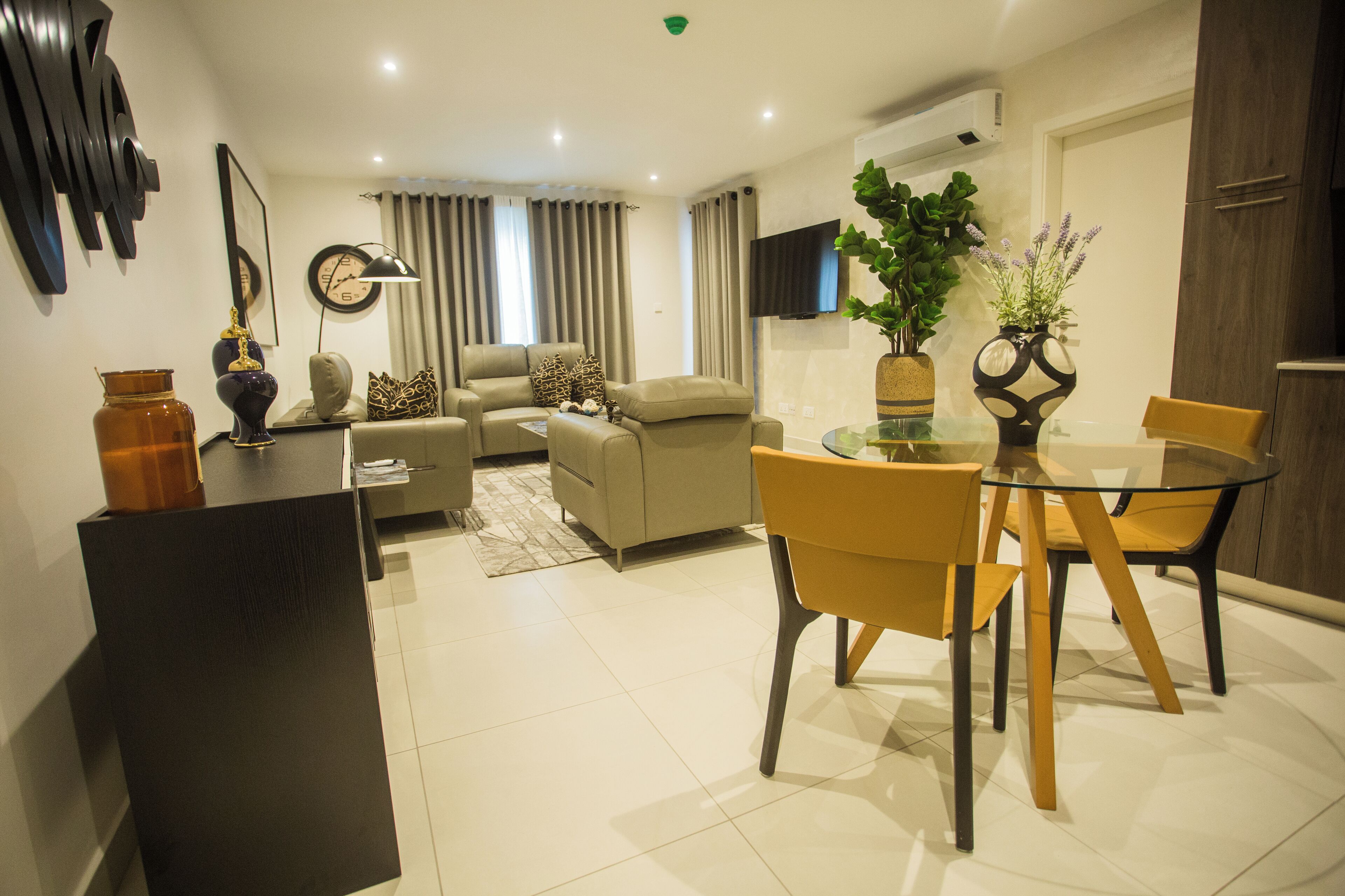 A modern living room with a sofa, armchairs, and a glass dining table.