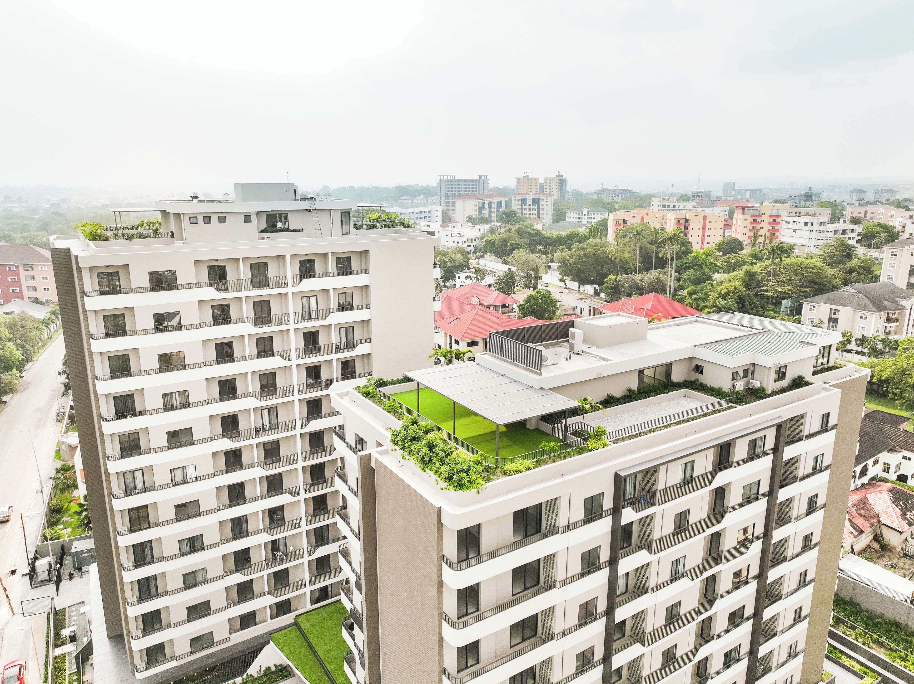 A high-rise building with multiple balconies and a rooftop garden.