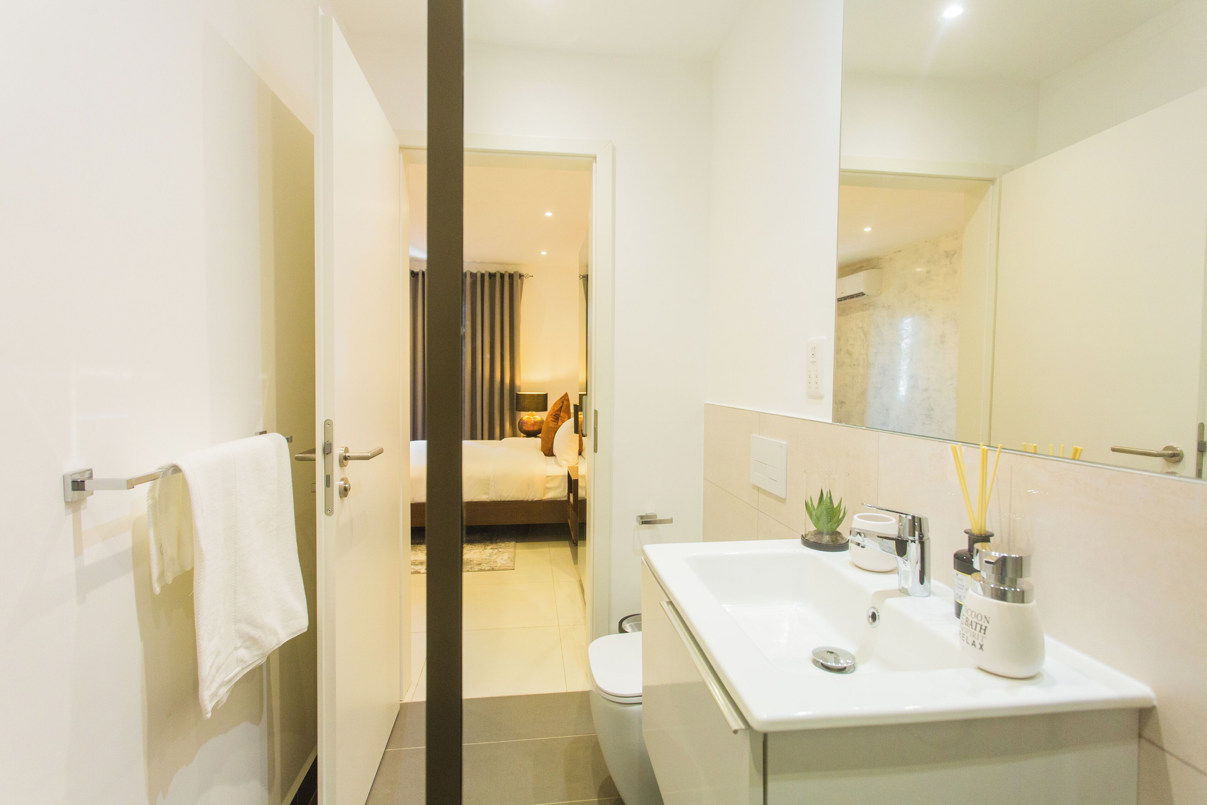 A modern bathroom with a glass-enclosed shower, a white sink with a soap dispenser, and a toilet.