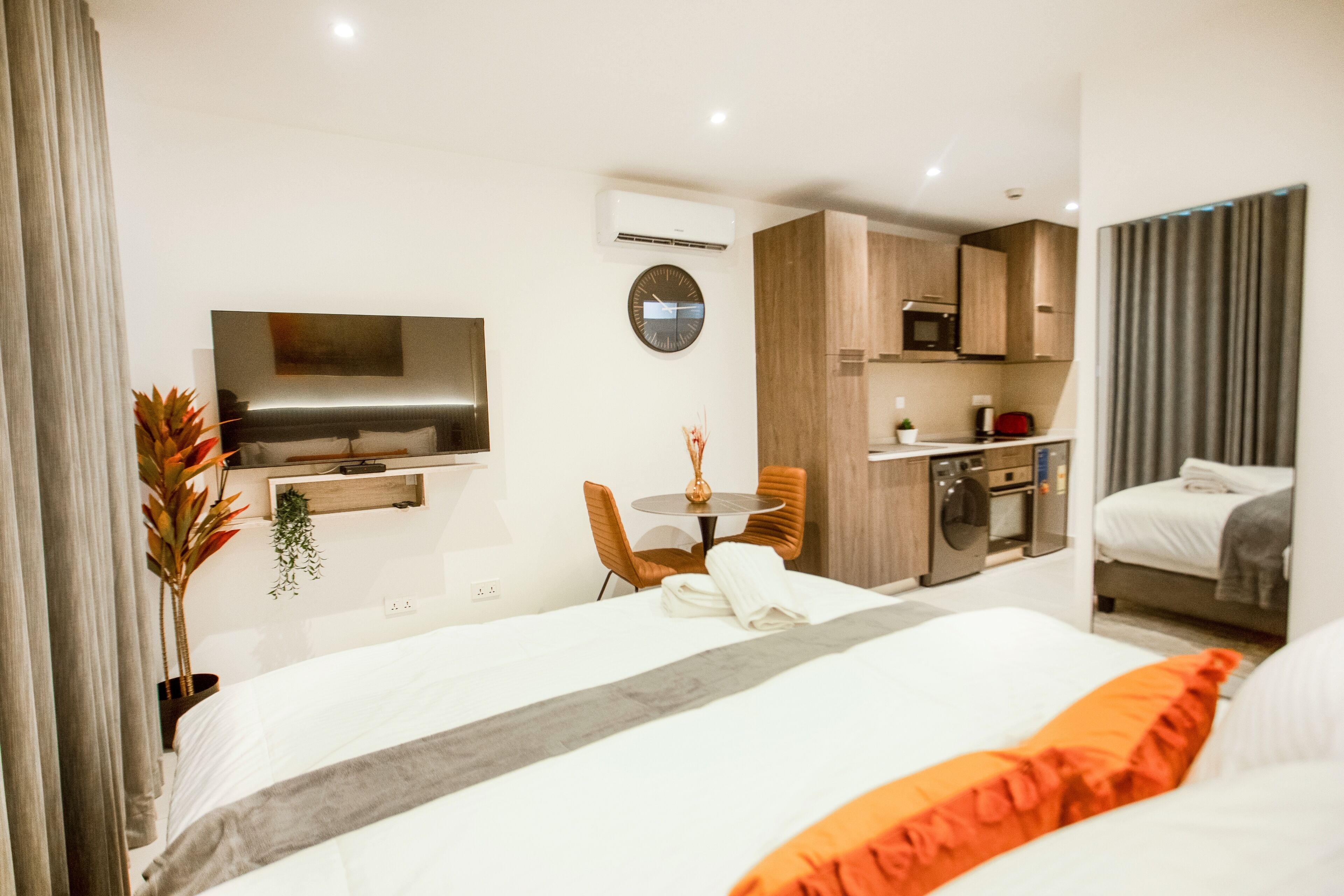Een hotelkamer met een bed, een televisie, een eettafel met stoelen, een keukenhoek en een badkamer.