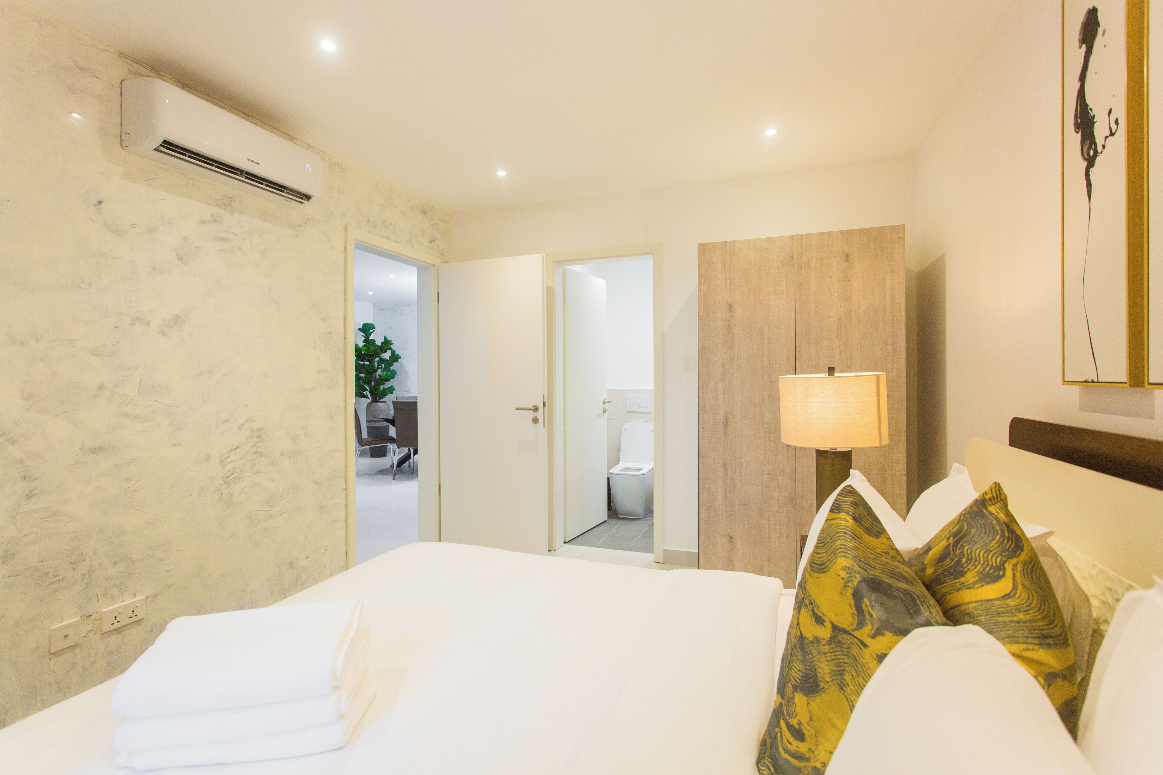 Habitación de hotel con cama, lámpara de noche, espejo y vista al baño.