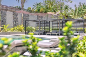 Un espace piscine doté de chaises longues et d’une pergola.