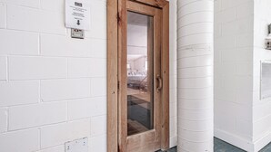 A wooden door with a glass panel, a white brick wall, and a white column. - Studio right at Sunday River (Newry)